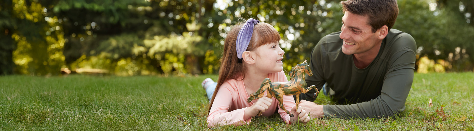 An adult and child with the Honor model lying in grass.