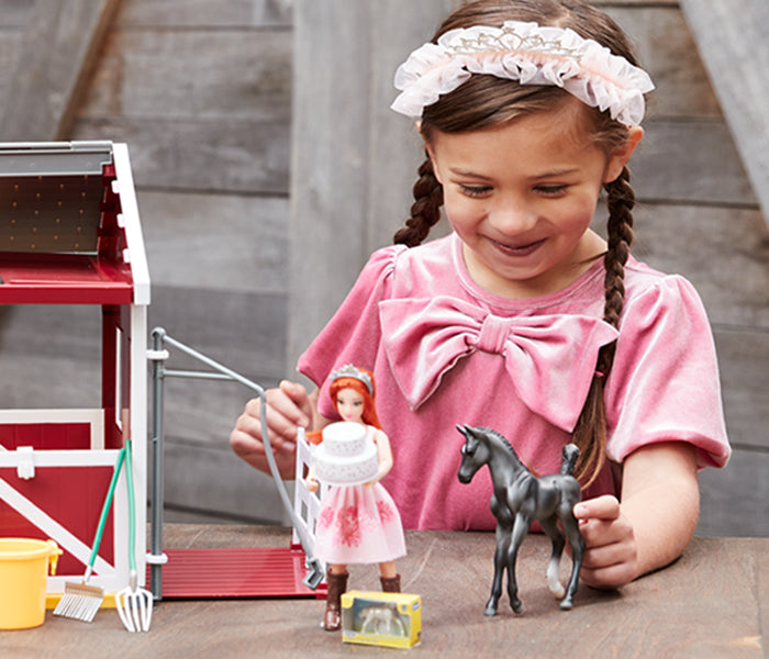 A girl playing with the Birthday at the Barn playset with a real barn in the background