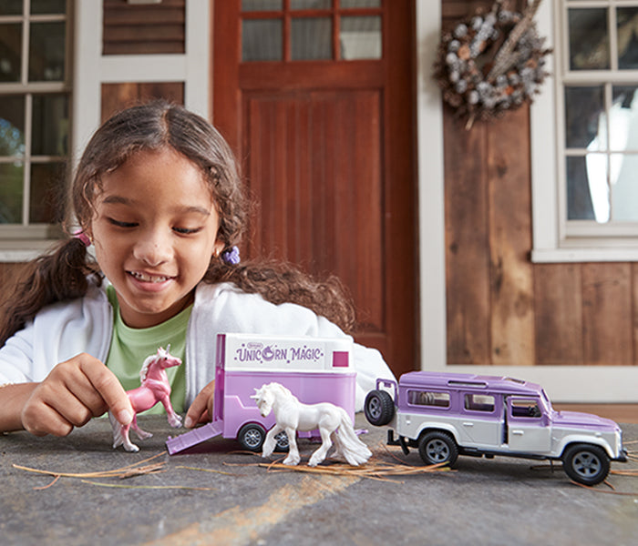 A girl playing with the Unicorn Magic Land Rover & Tag-A-Long Trailer © outside
