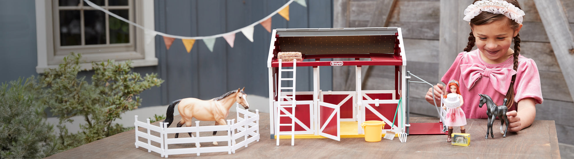 A girl playing with the Birthday at the Barn playset with a real barn in the background