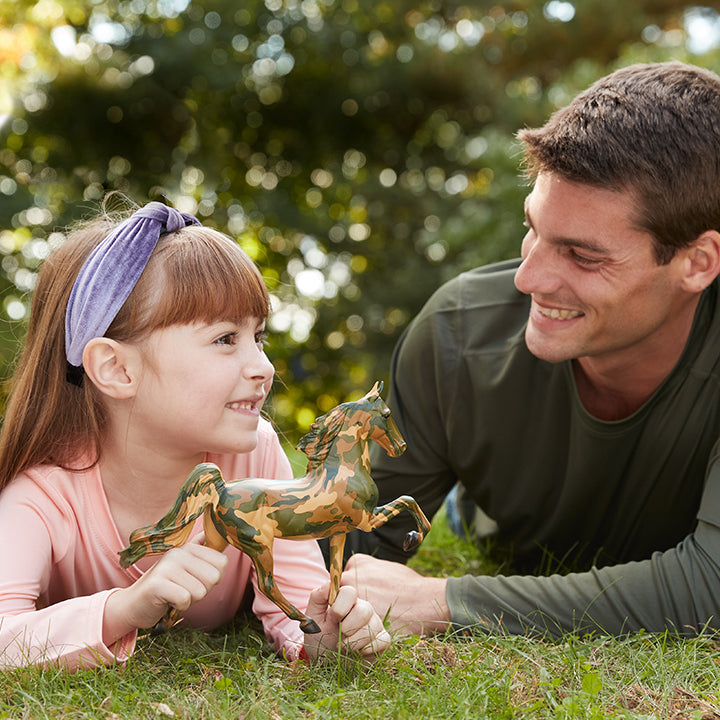 A child and adult laying in the grass with Honor, the 2025 Hope Model