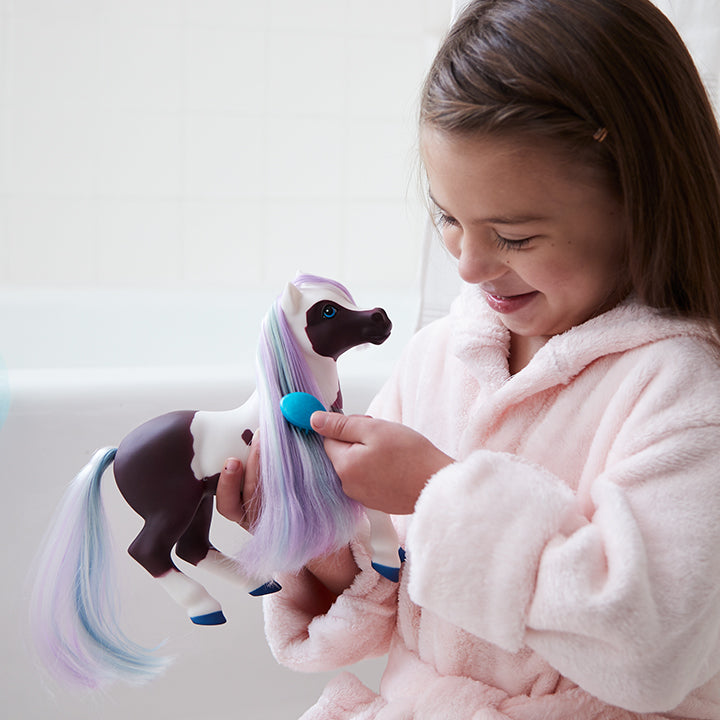 Lucky Acres Collection - A girl brushing the hair of a bath toy.