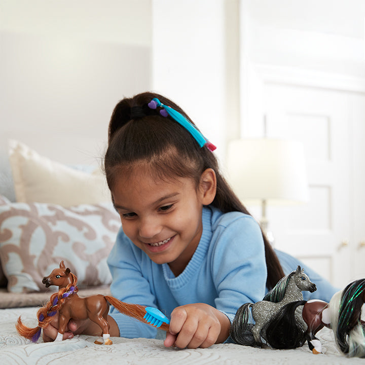 The Mane Beauty Collection - featuring a girl playing with models on a bed.