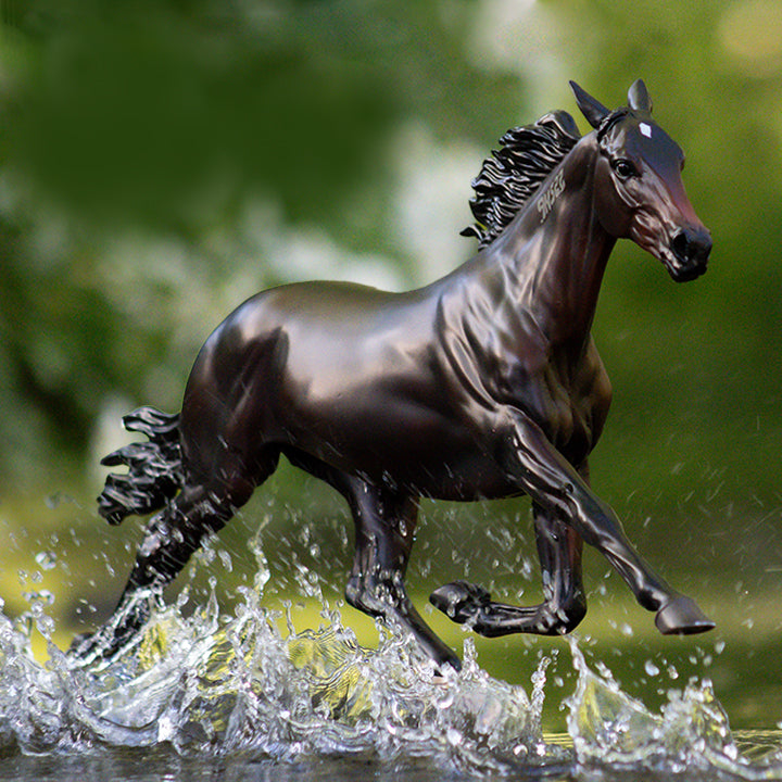 A Breyer racehorse running through water in an outdoor setting.