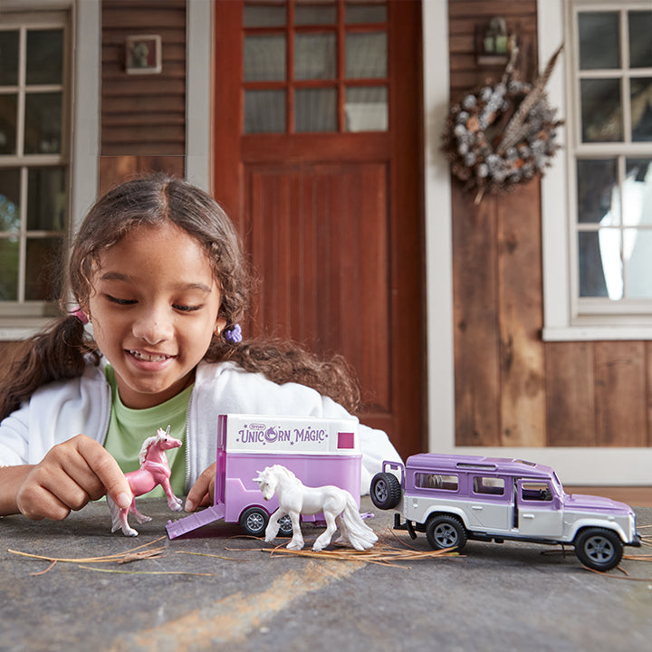 A child playing with the Unicorn Magic Land Rover & Tag-A-Long Trailer © outside .