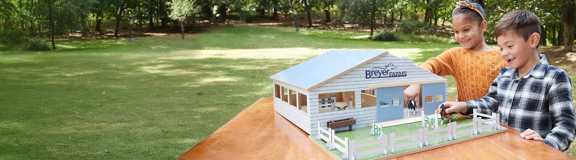 Home for the Holidays Desktop Banner - Two kids playing with a Breyer Barn