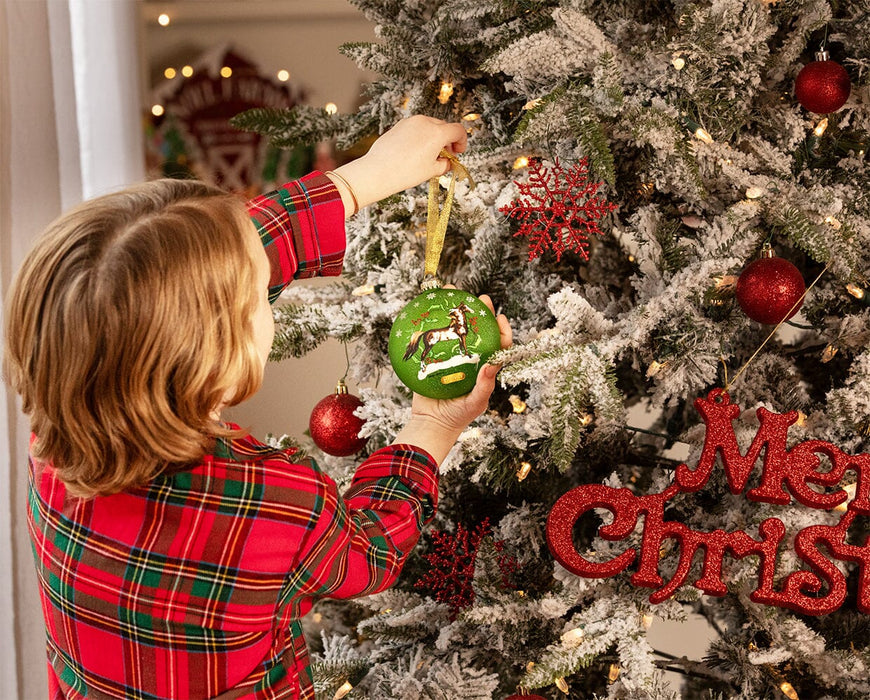 A child putting the American Saddlebred | Artist Signature Ornament on a Christmas tree