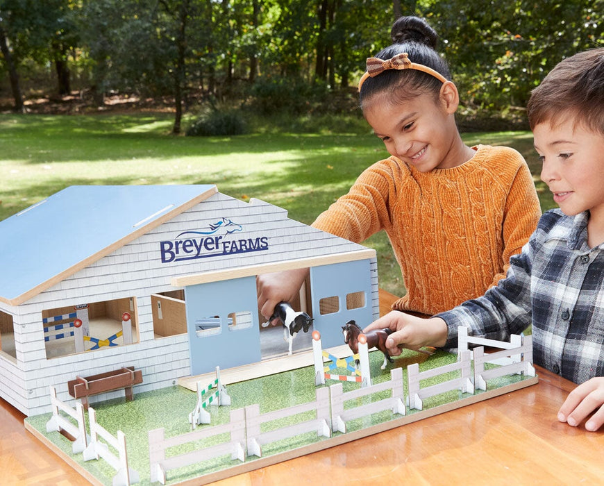 Two children playing with the Deluxe Arena Stable outside on a table