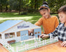 Two children playing with the Deluxe Arena Stable outside on a table