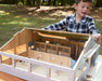 A boy playing with the Deluxe Arena Stable outside on a table