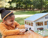 A girl playing with the Deluxe Arena Stable outside on a table