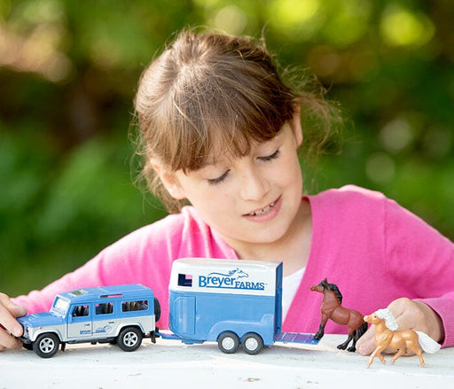 A child playing with the Breyer Farms™ Land Rover® and Tag-A-Long Horse Trailer