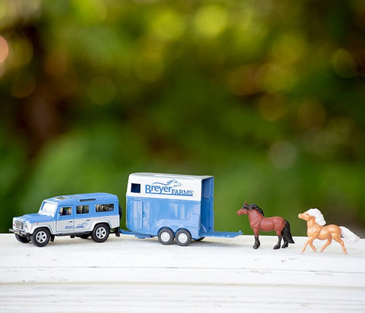 The Breyer Farms™ Land Rover® and Tag-A-Long Horse Trailer on a railing outside.