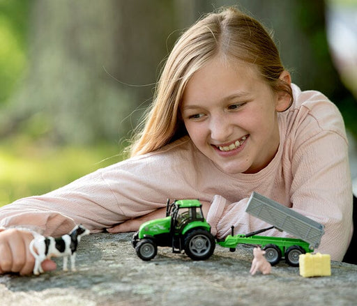 A girl playing with the Breyer Farms™ Tractor and Tag-A-Long Wagon