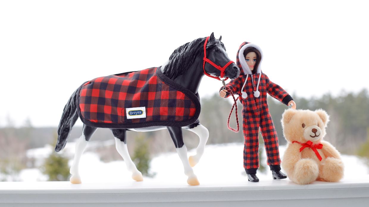 Holiday Pajama Party with Cinders, a tobiano pinto pony wearing buffalo plaid blanket, Christy in buffalo plaid pjs, and teddy bear