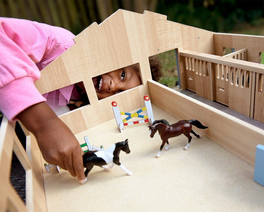 A girl playing with the Deluxe Arena Stable with the roof off