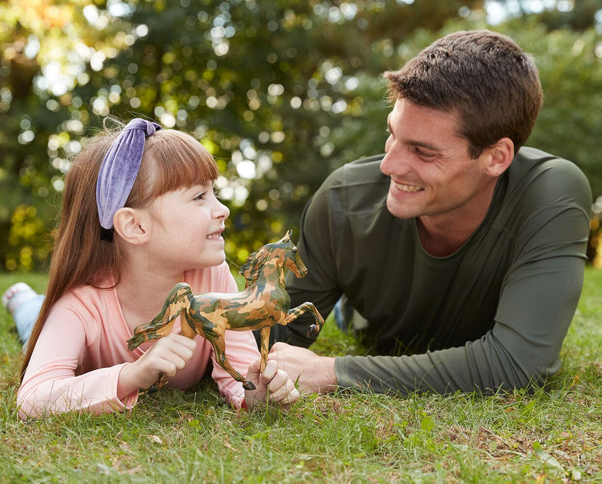 Honor | 2025 Hope Horse - a child holding the model with an adult in the grass