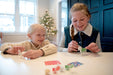 Two girls painting horse ornaments in front of a Christmas tree