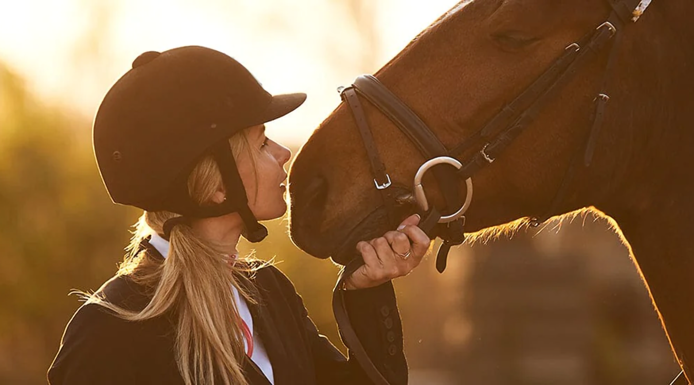 Woman rider holding horse close to face