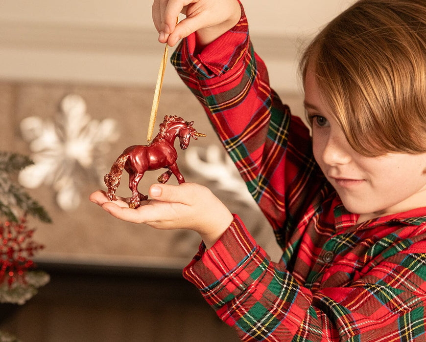 A child displaying the Scarlet | Unicorn Ornament